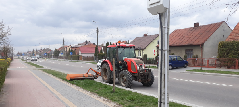 mężczyzna kosi trawę kosiarką podczepioną do traktora